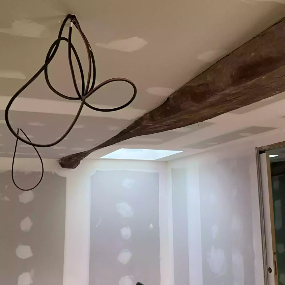 Préparation du raccordement électrique pour volet motorisé dans mur de pierre par Jagaud Petit SARL.