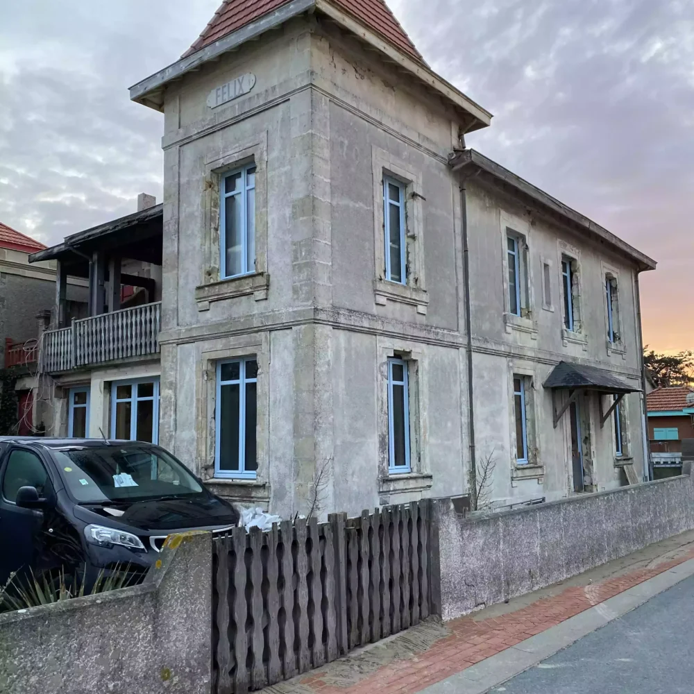 Rénovation par Jagaud Petit : Détail des menuiseries bois bleu clair et garde-corps assorti sur maison de caractère.